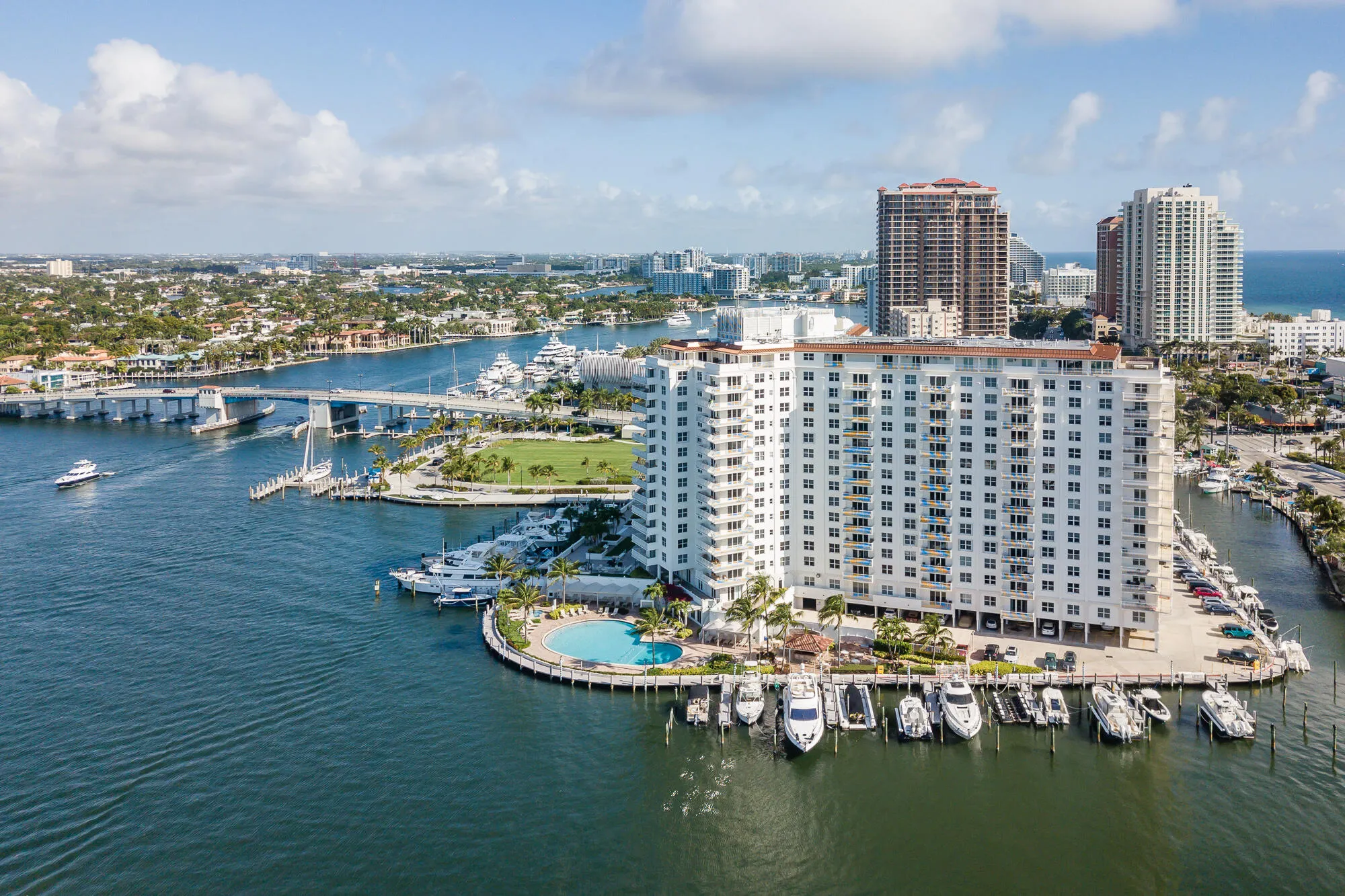 High-rise building with a waterfront location, circular outdoor pool, private boat slips, and a multi-level parking structure
