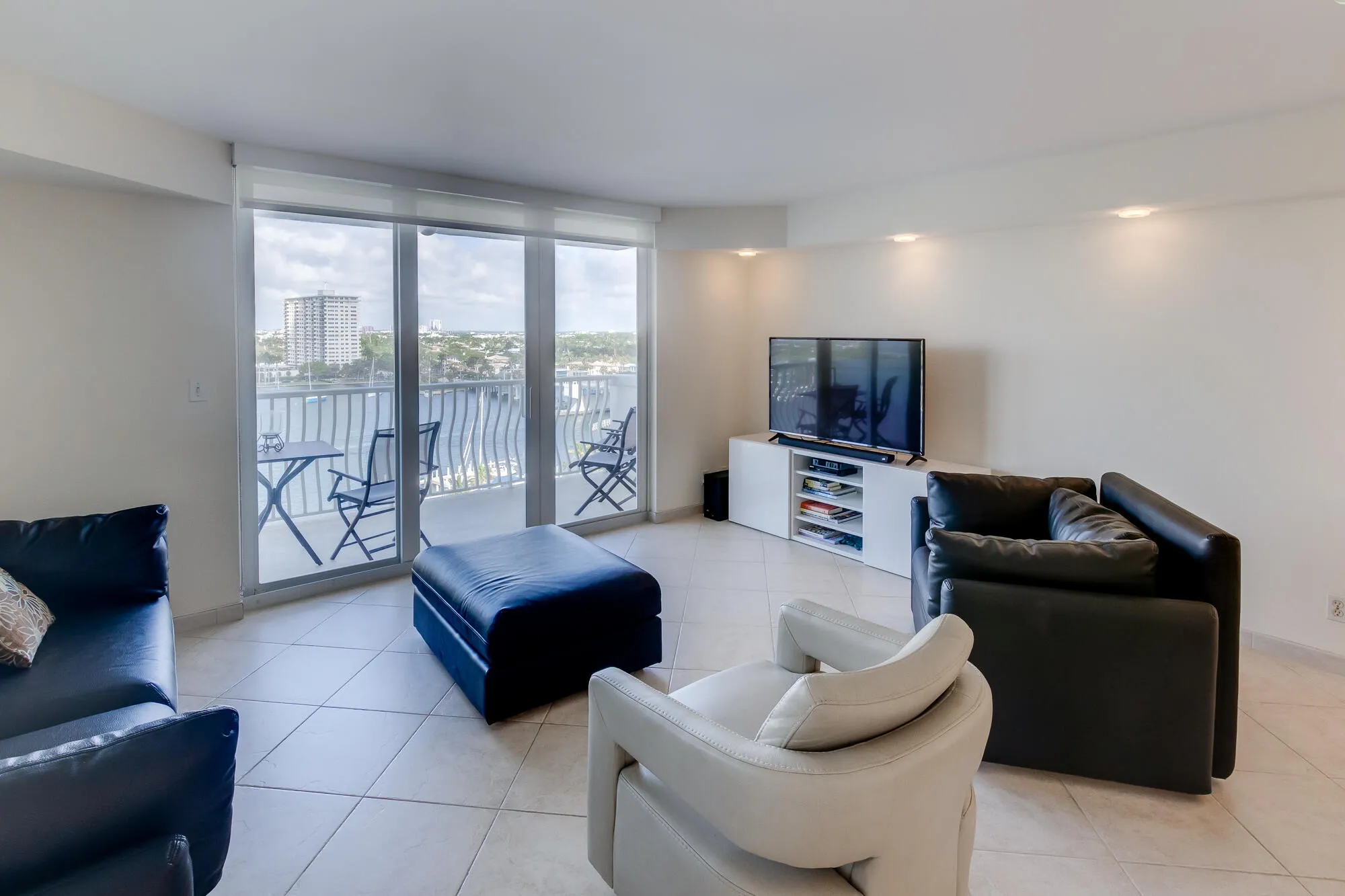 Expansive glass sliding doors open to a balcony with metal railings and water scenery