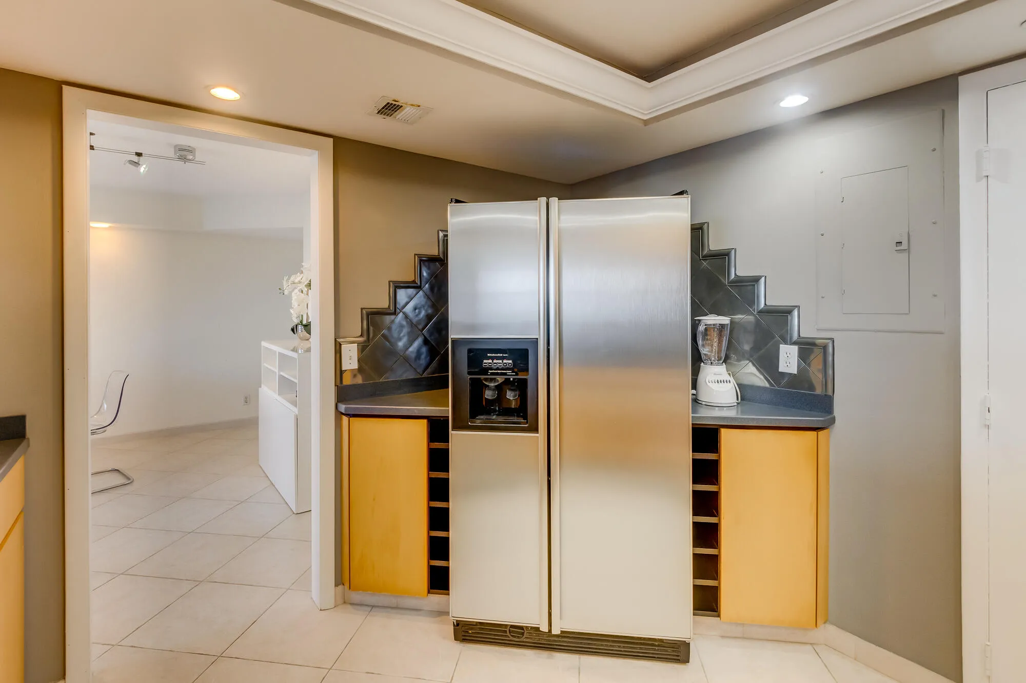 Stainless steel refrigerator, built-in wine storage, tile flooring, recessed lighting, and crown molding