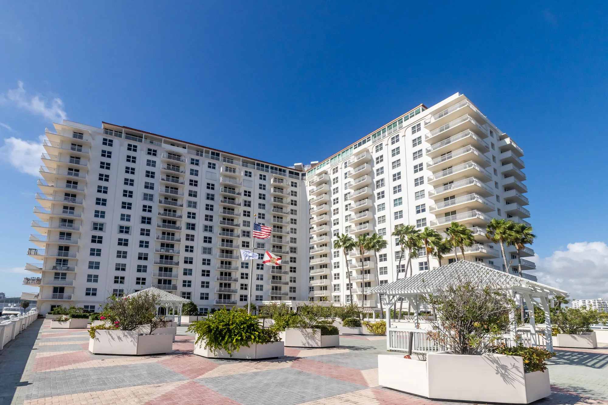 Multi-story building featuring multiple private balconies, a rooftop amenity area, and a decorative pergola
