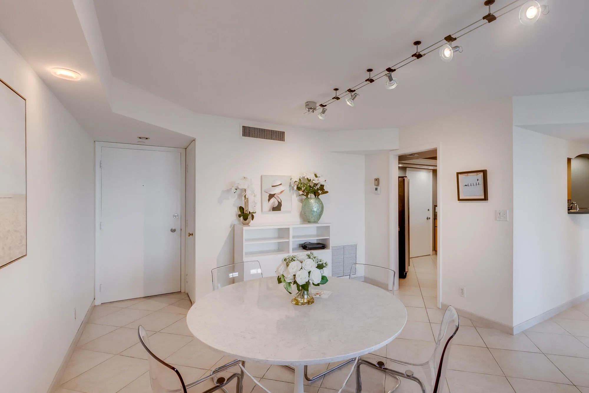 Recessed lighting, track lighting system, built-in shelving unit, white walls, and tiled flooring