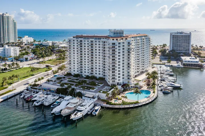 Multi-story building featuring balconies, ground-level swimming pool, and a private marina with multiple boat slips