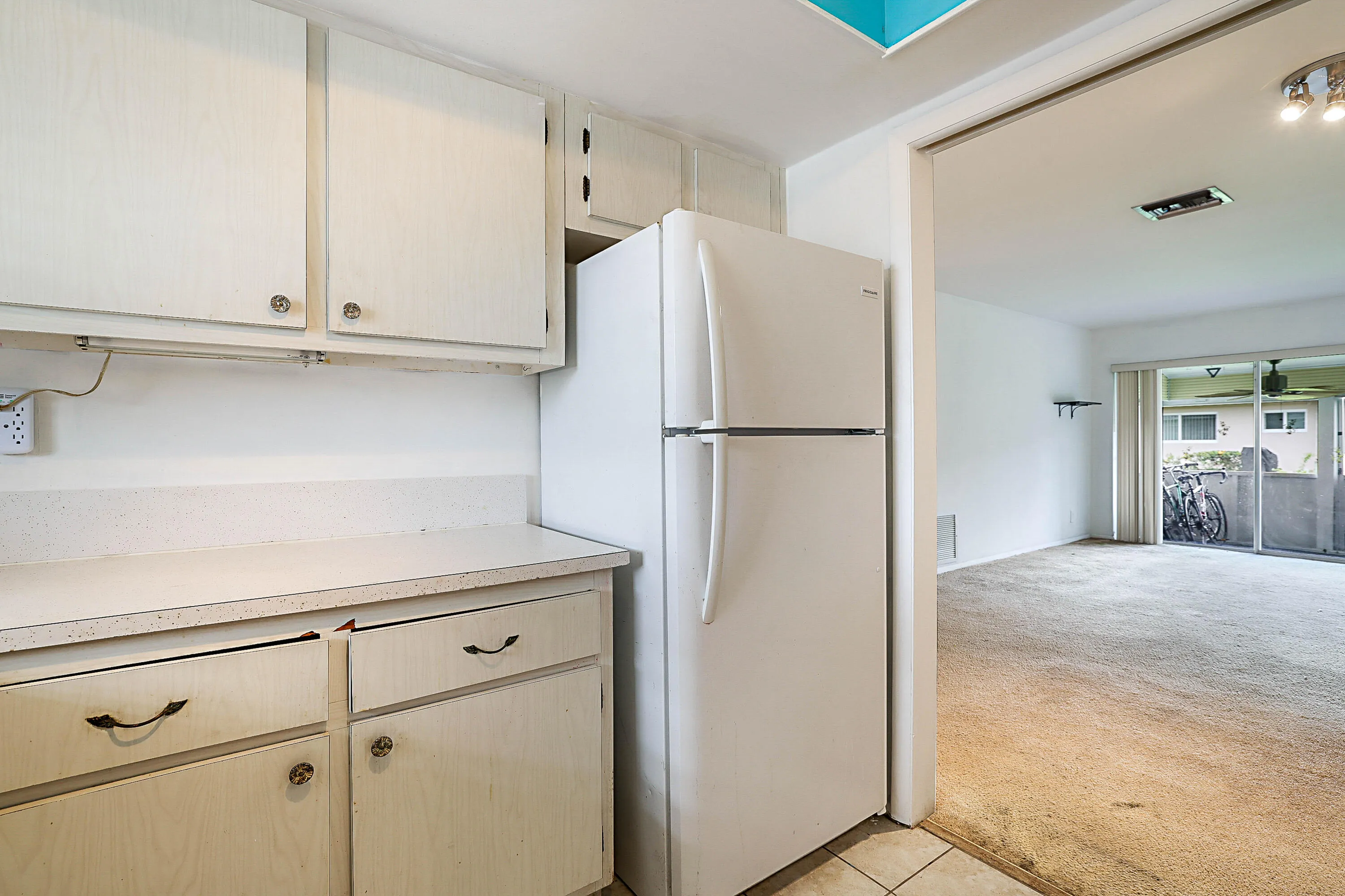 Kitchen featuring white cabinetry with dark hardware and white countertops, adjacent to dining/Living room