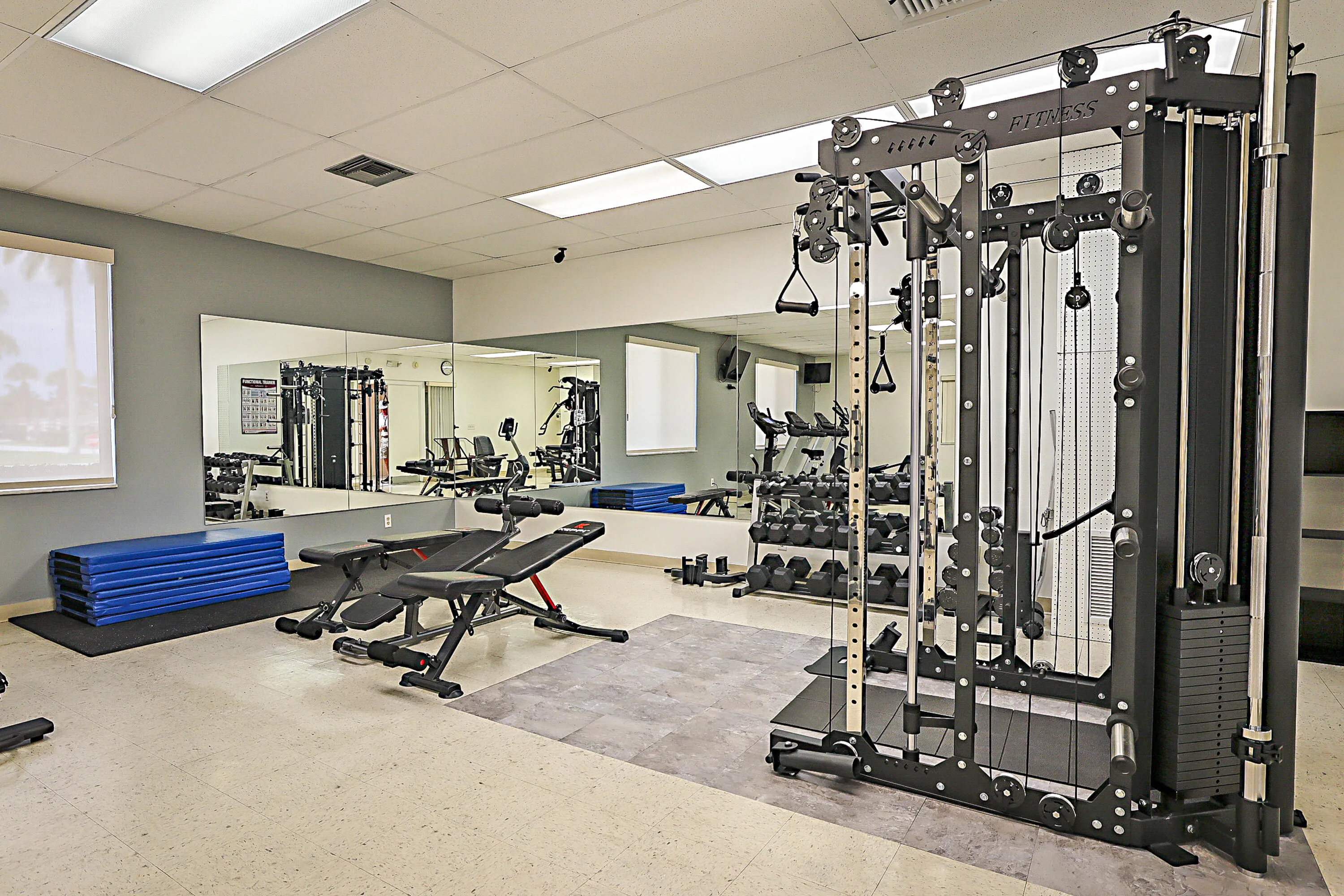 Fitness area featuring large wall-mounted mirrors, recessed lighting, and ample natural light from multiple windows