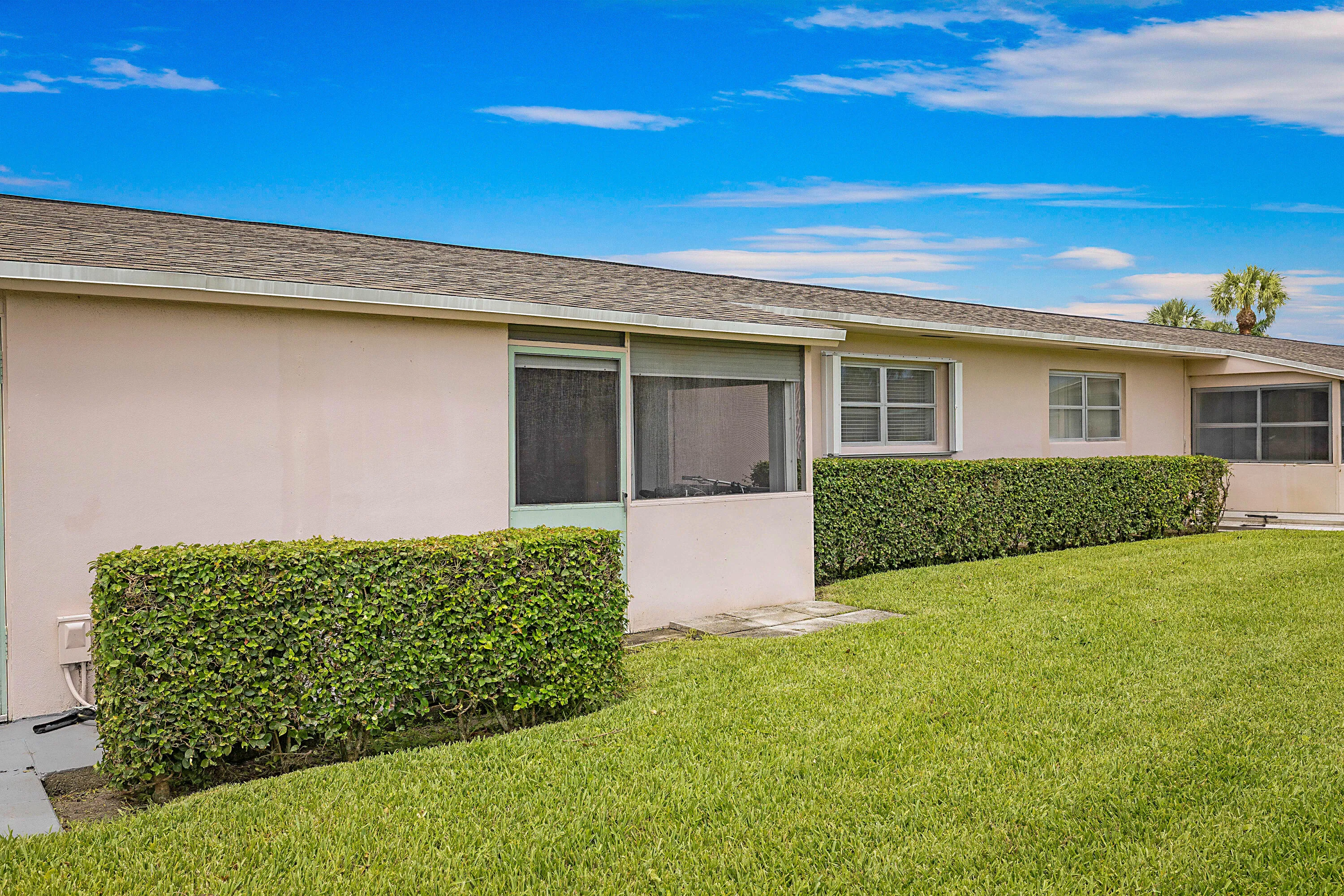 Manicured lawn with mature shrubbery and a screened patio