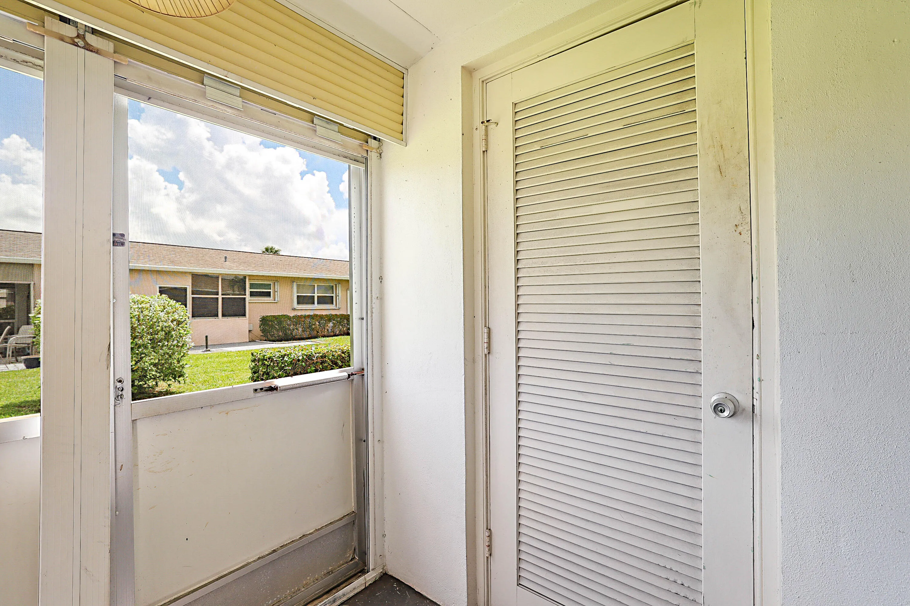 Screened enclosure with aluminum framing and louvered door