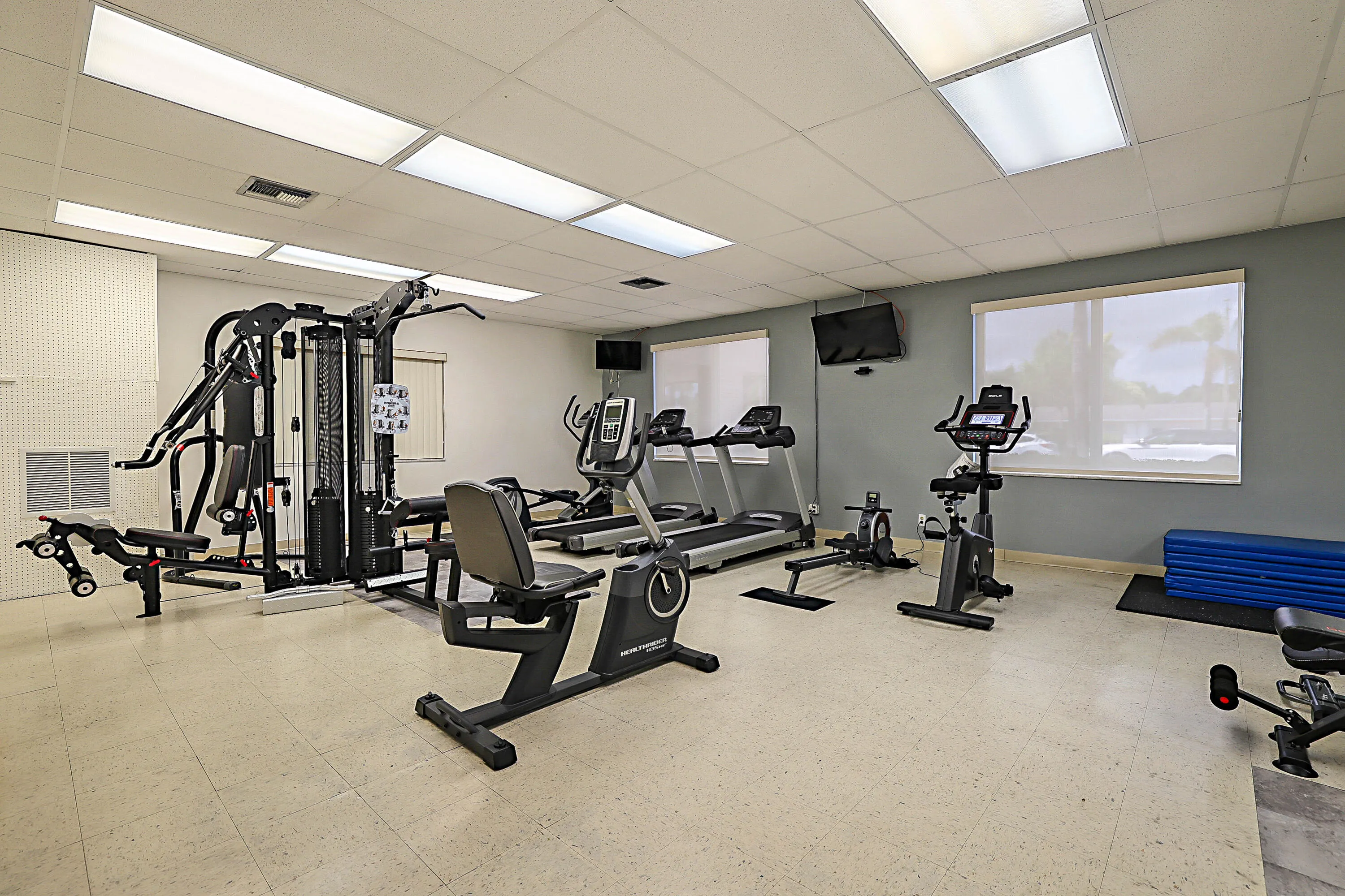 Spacious fitness area featuring commercial grade equipment, multiple windows, and recessed lighting