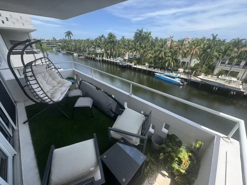 Balcony with water frontage featuring a white railing, artificial turf flooring, and a sliding glass door