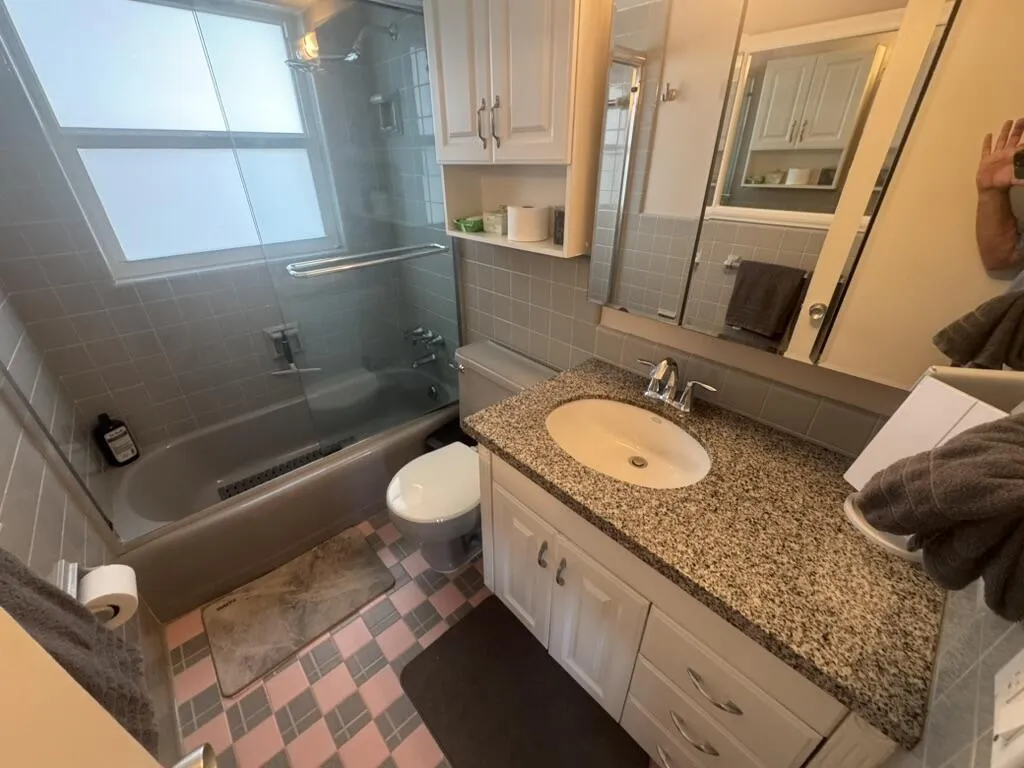 Bathroom featuring a white vanity with a speckled countertop, an integrated sink, and white cabinetry
