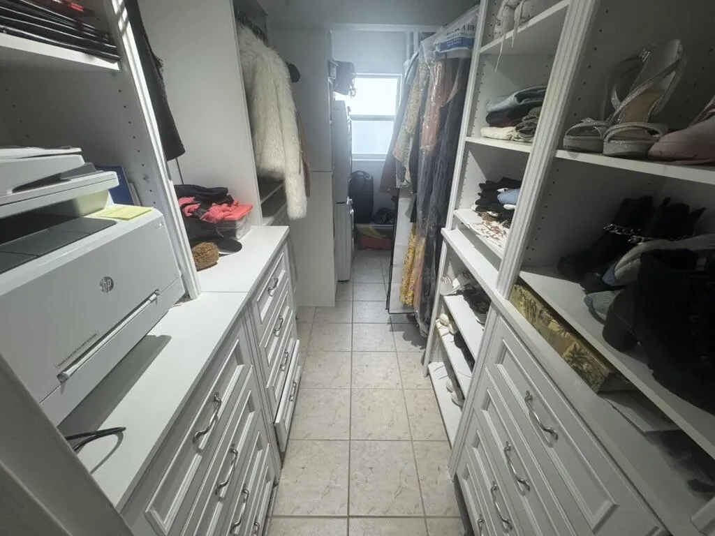 Custom closet system featuring built-in shelving, multiple drawers with decorative pulls, and tile flooring