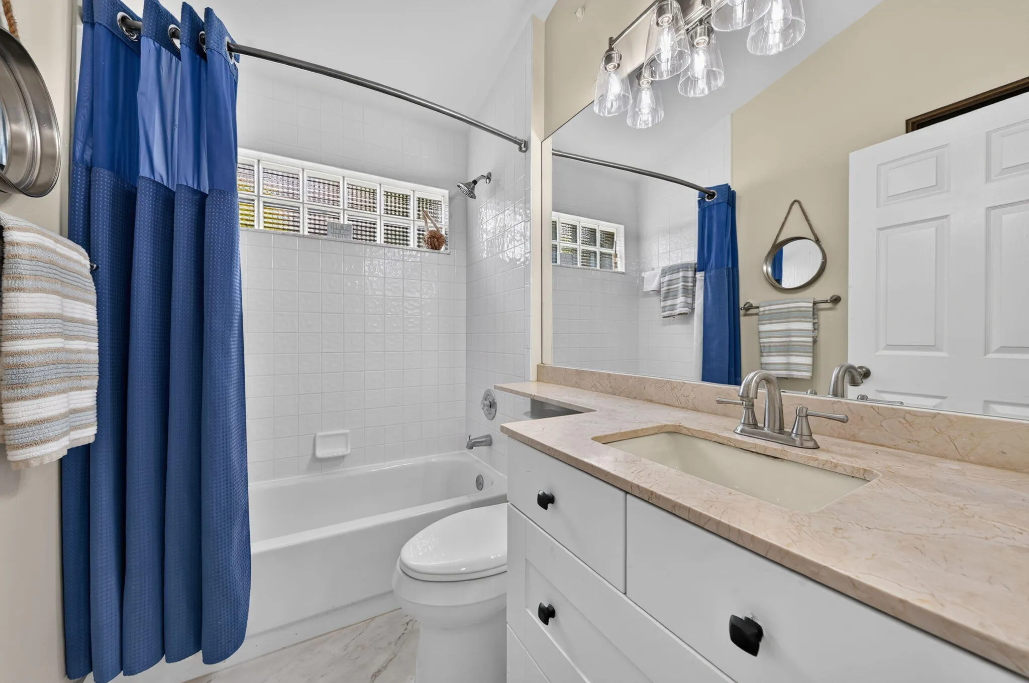 White vanity with dark hardware, integrated sink, and light-toned countertop