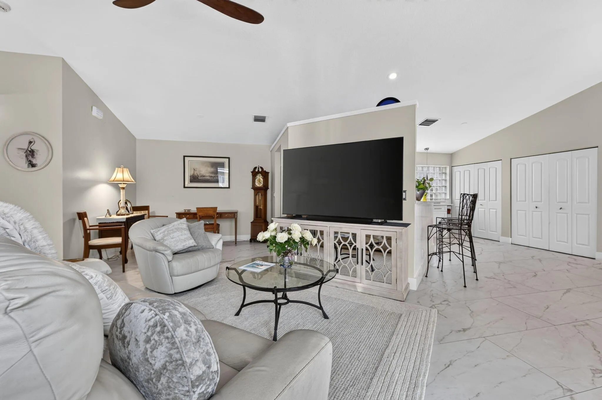 Vaulted ceilings, a ceiling fan, and light-toned walls with marble-patterned tile flooring