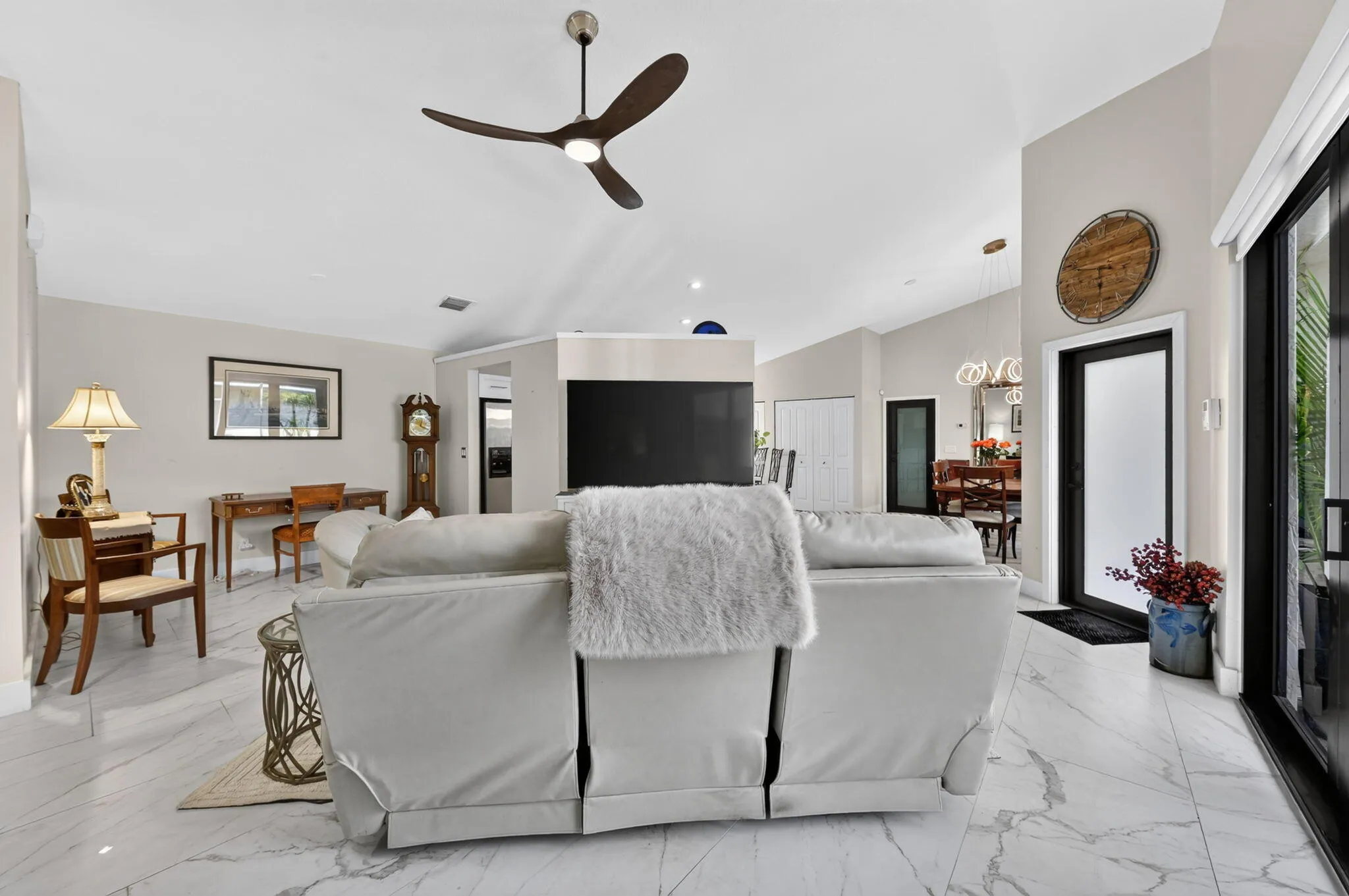 Vaulted ceiling, modern ceiling fan, large format tile flooring, black-framed sliding glass door, and black-framed interior doors