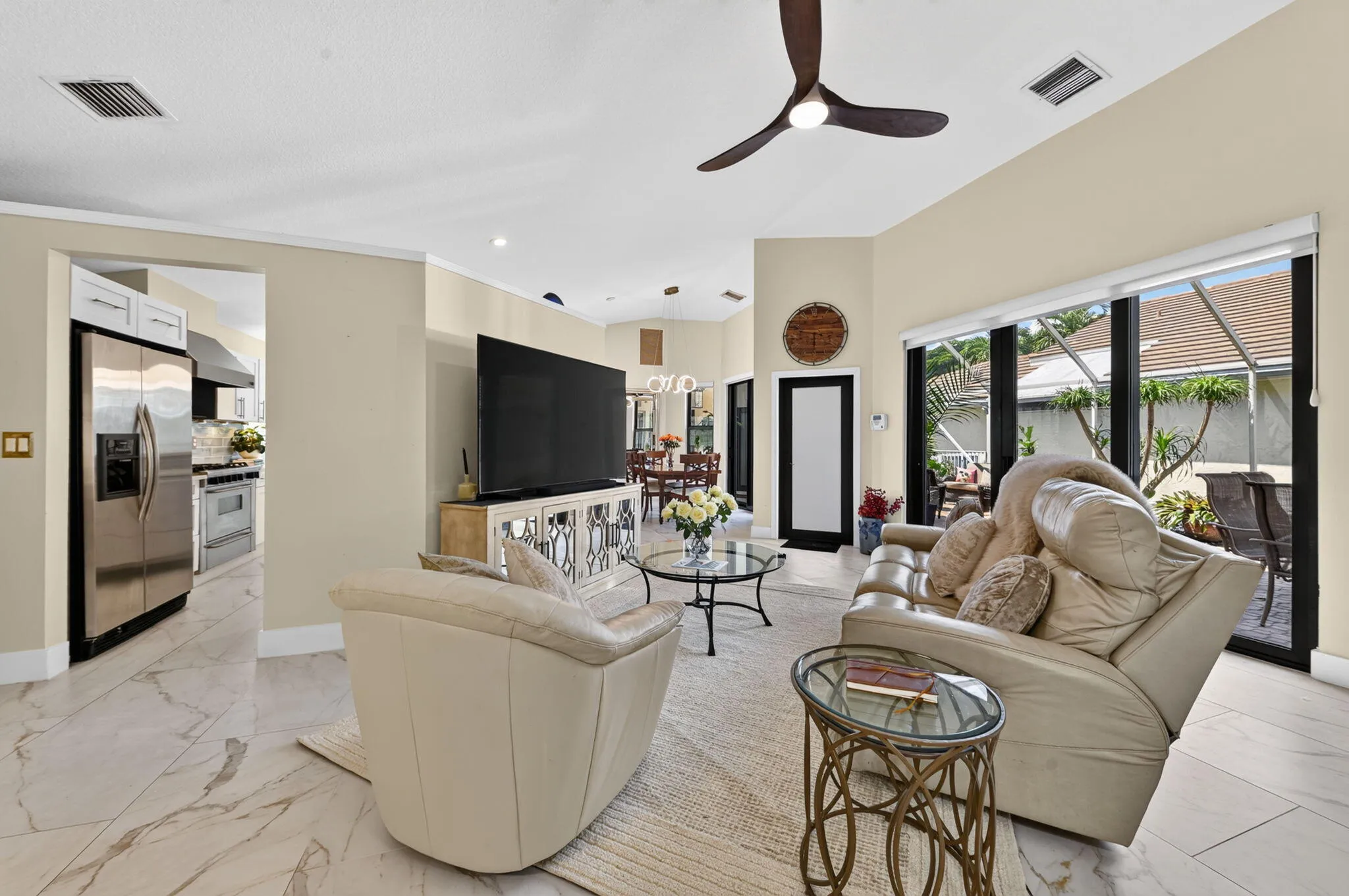 Vaulted ceilings with a ceiling fan, large format tile flooring, and sliding glass doors to the exterior