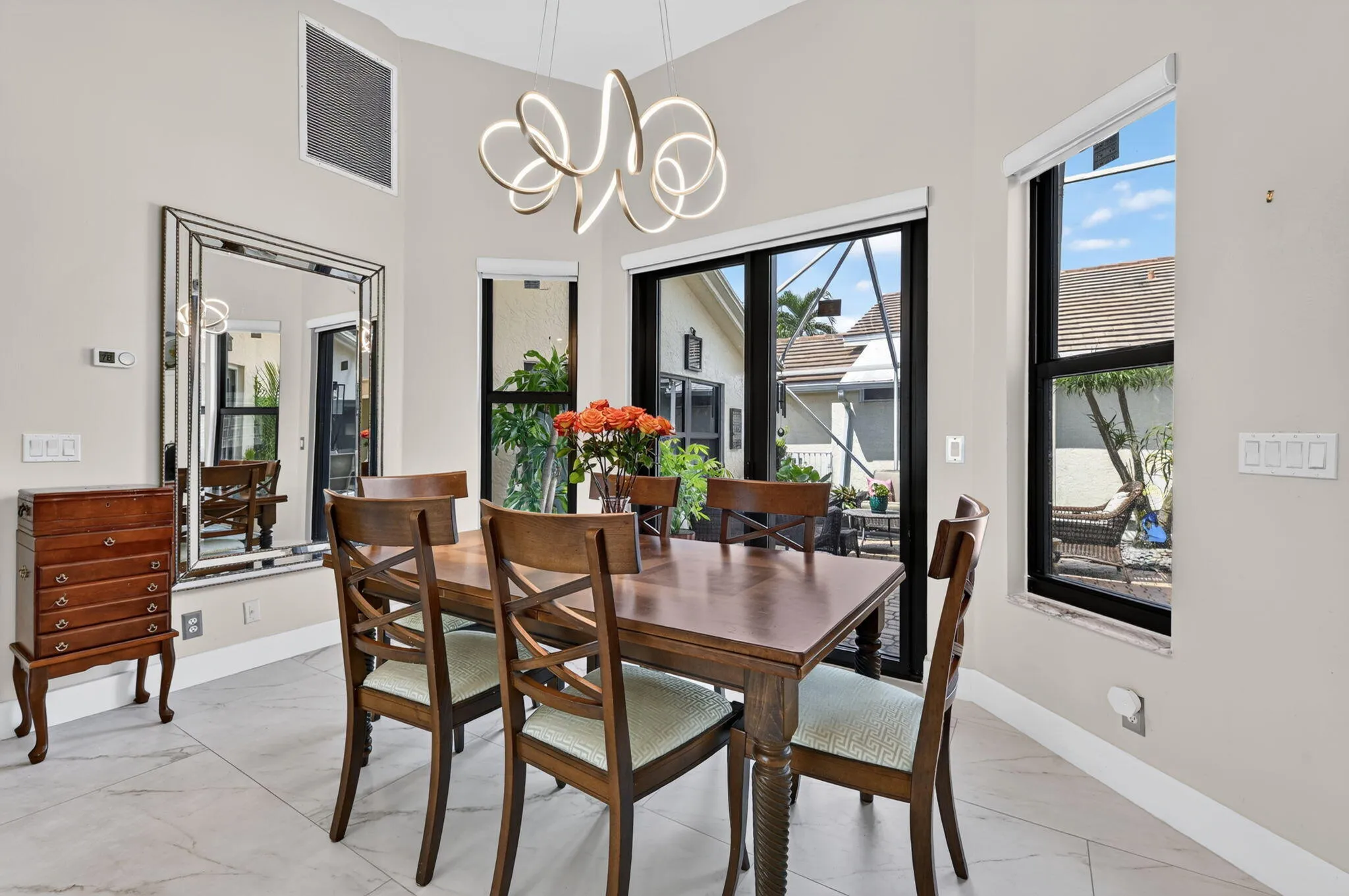Vaulted ceiling with a contemporary light fixture, simulated marble flooring, slider from dining to courtyard and large windows (all impact).