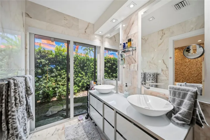Bright, sophisticated primary bathroom with serene garden views, creating a fresh and relaxing atmosphere.