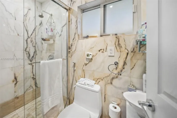 Modern full bathroom featuring marble-style finishes and a glass-enclosed walk-in shower. En-suite of Secondary Bedroom 1
