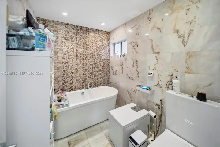 A beautifully finished primary bathroom featuring a relaxing soaking tub and refined marble-inspired details.