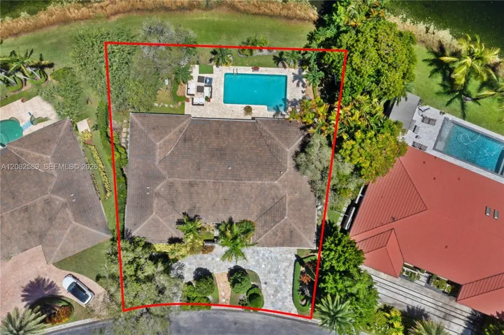 Top-down aerial view highlighting the property’s generous lot, private pool, landscaped grounds, and lake setting.