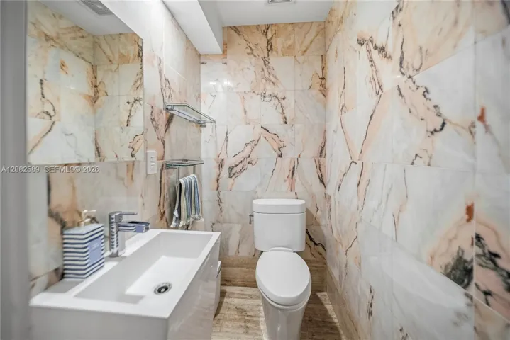 A stylish powder room featuring sleek fixtures and beautiful marble-inspired finishes.