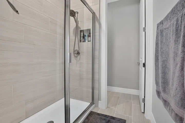 Walk-in shower with clear glass enclosure, a built-in shower niche, and a brushed nickel shower head