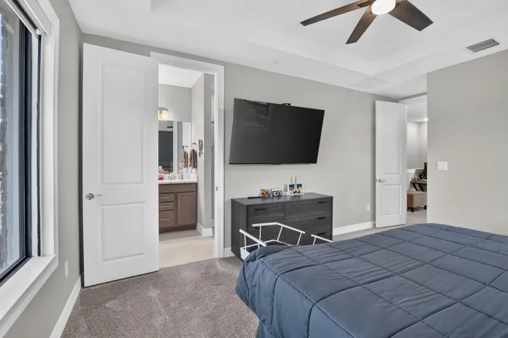 Tray ceiling with a ceiling fan, grey wall paint, and grey carpet flooring