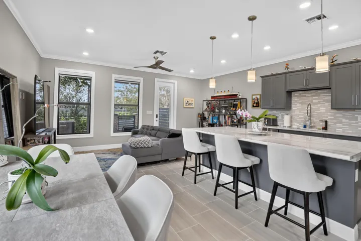 Open-concept living area featuring wood-finish flooring, recessed lighting, and crown molding