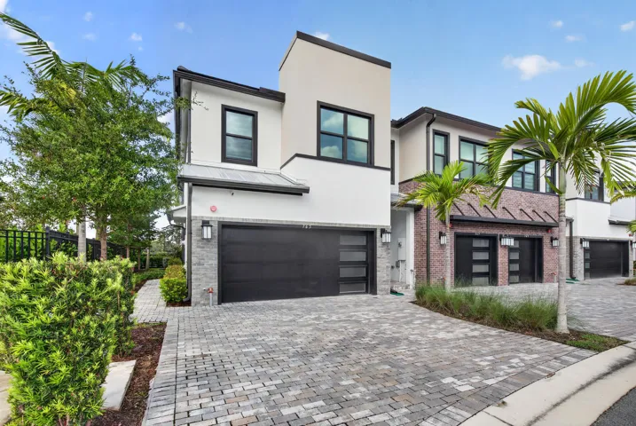 Modern architectural design featuring a clean-lined façade with stucco and brick exterior, black-framed windows, and contemporary detailing