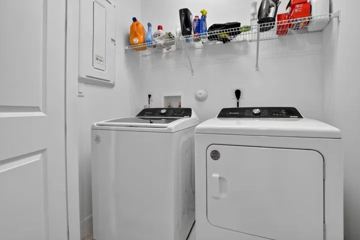 Dedicated laundry room featuring a top-load washer and electric dryer with digital controls, white finish cabinetry, overhead storage shelving, and utility sink with chrome fixtures