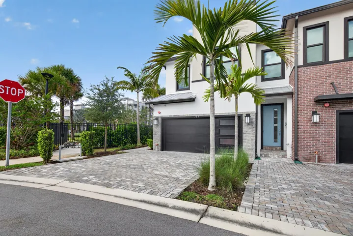 Modern exterior design with a paver driveway, an attached garage, and a light blue entry door