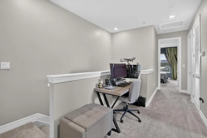 Carpeted loft area featuring recessed lighting, a white painted half-wall, and a ceiling access panel