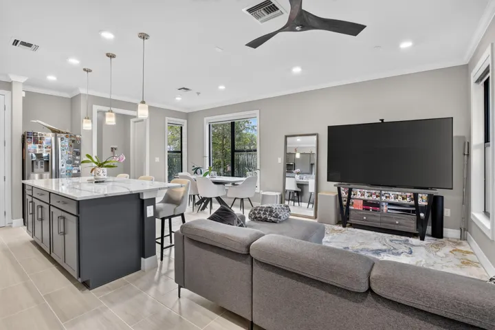 Open-concept living space with tile flooring, a kitchen island featuring a light-toned countertop, recessed lighting, and a modern ceiling fan