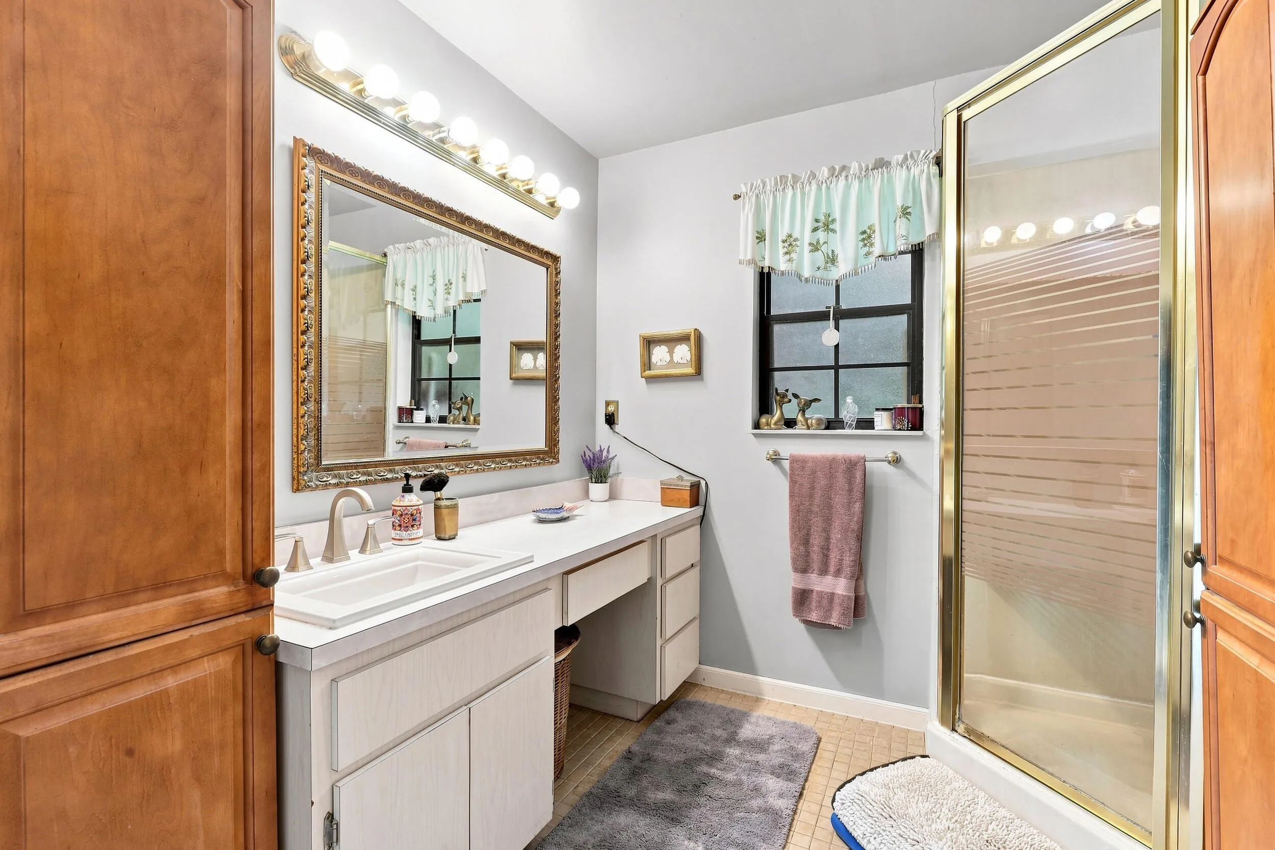 Bath featuring a spacious vanity, large mirror, and glass-enclosed shower.