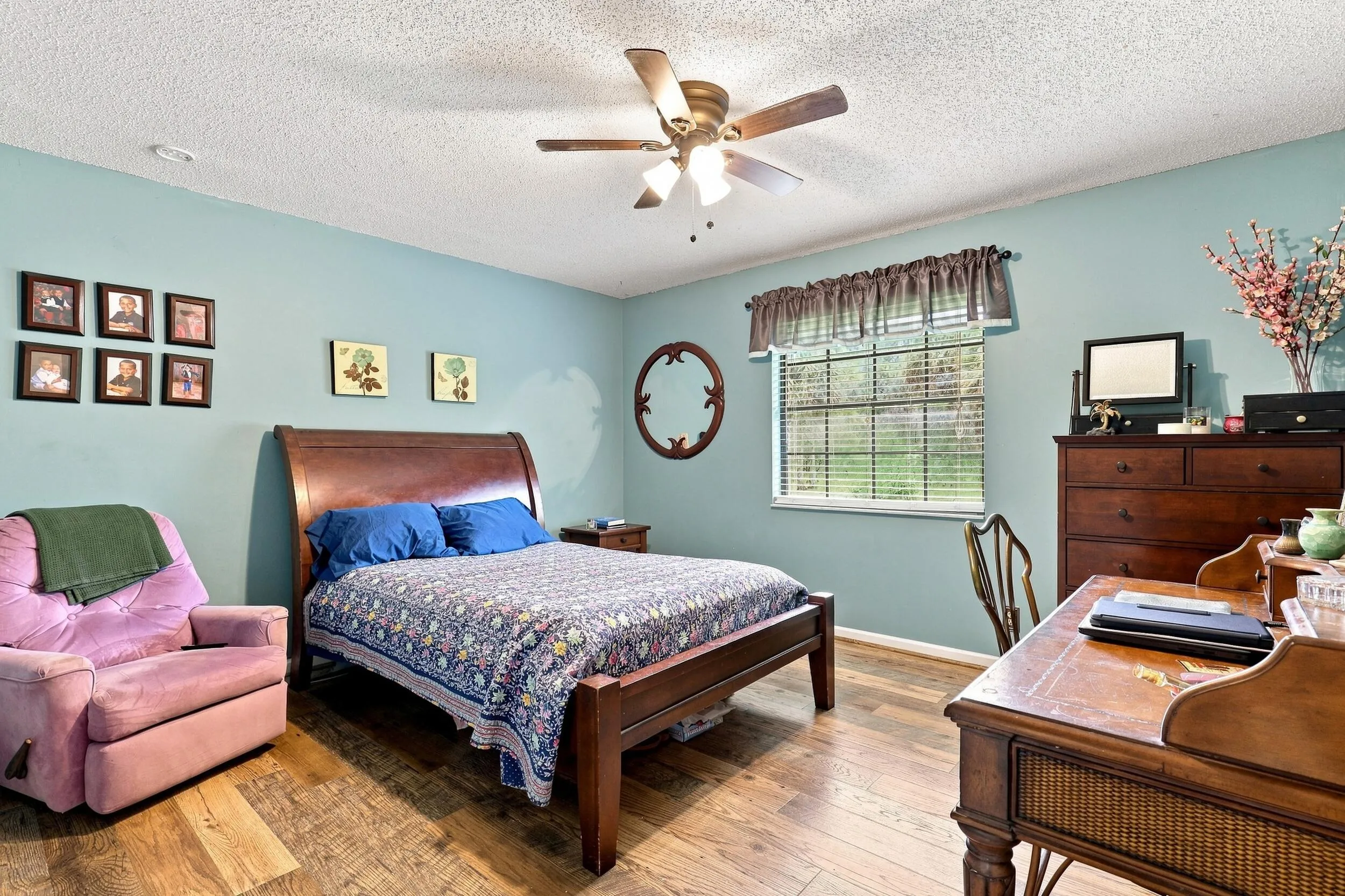 Spacious bedroom with ceiling fan, natural light, and room for additional furnishings.
