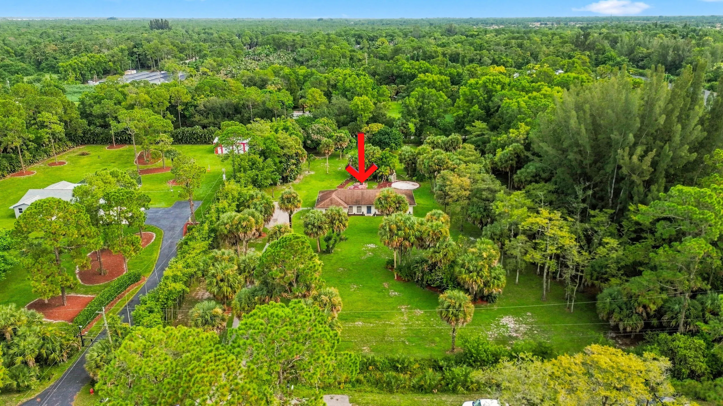 Elevated aerial view highlighting the home and its spacious acreage setting surrounded by mature trees.