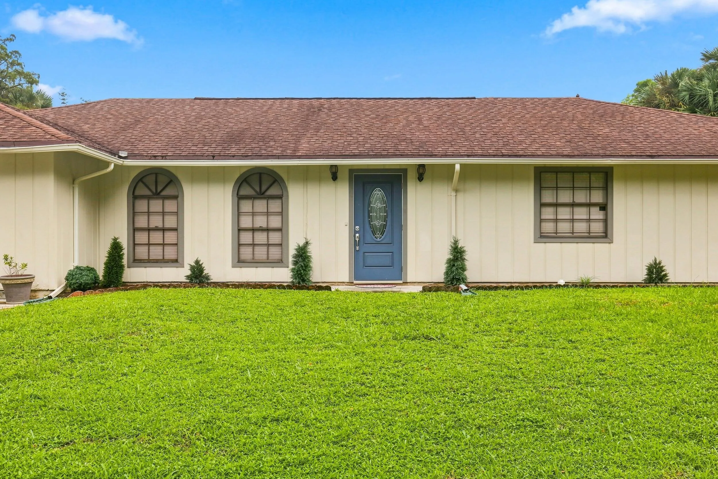 Closer exterior view showcasing the home, expansive front lawn, and covered entry.
