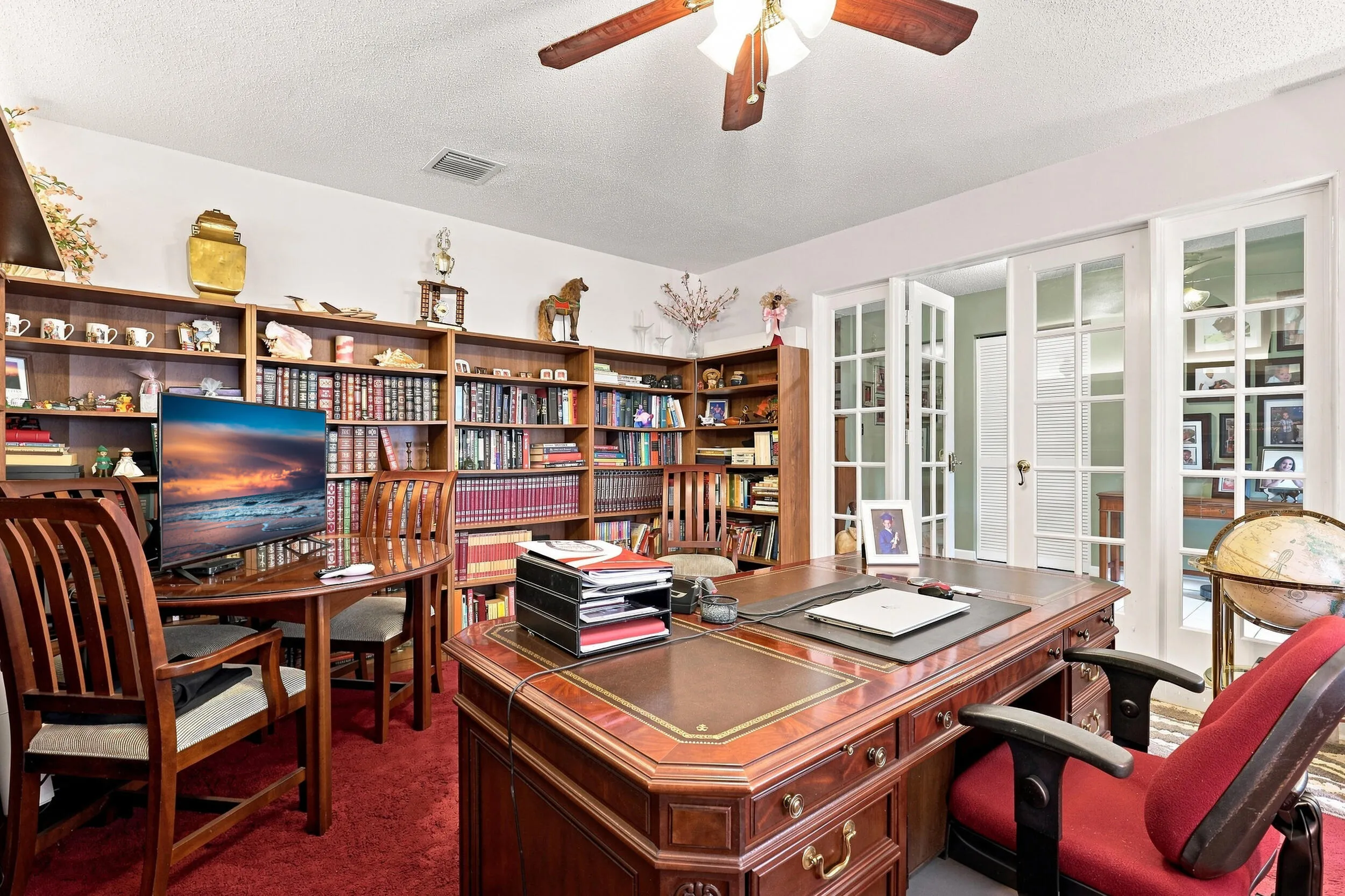 Spacious dedicated office featuring extensive built-in shelving, ceiling fan, and plenty of workspace.