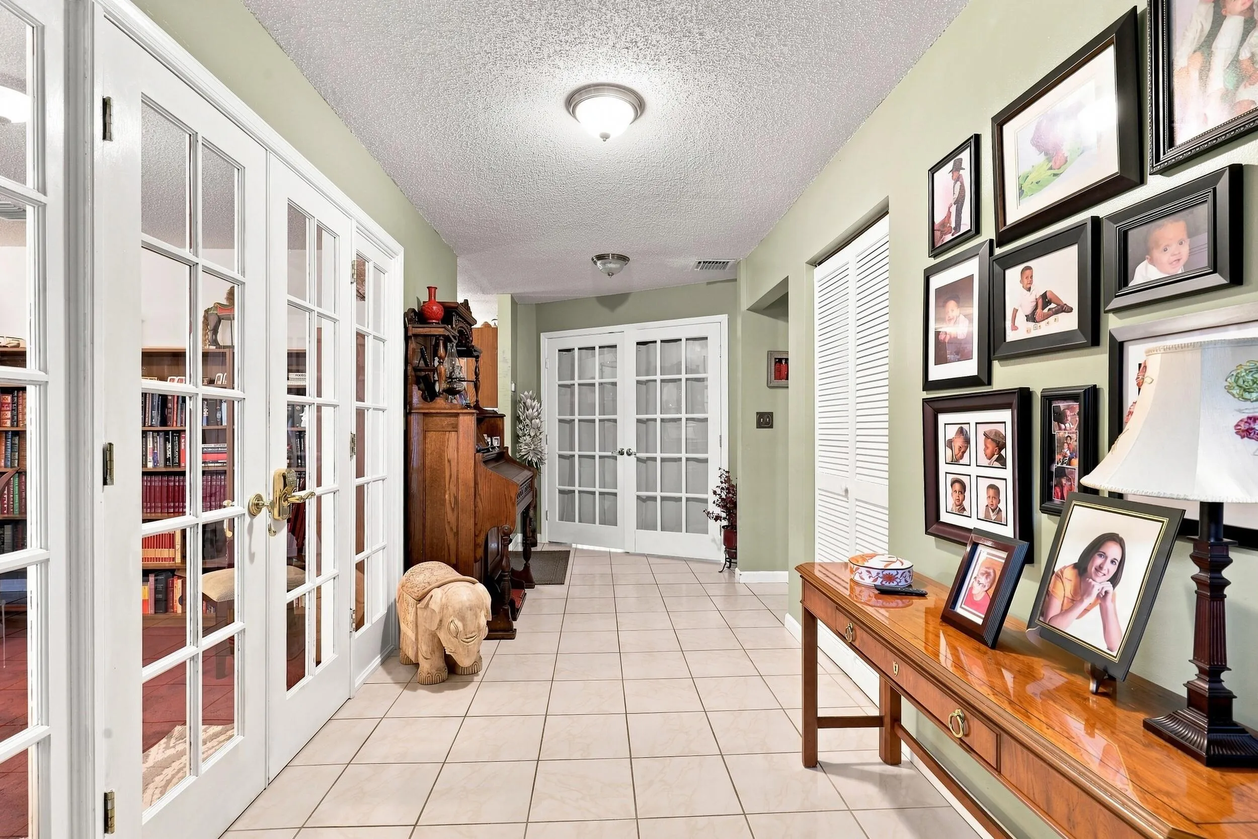 Bright interior hallway with tile flooring, built-in shelving, and plenty of display and storage space.
