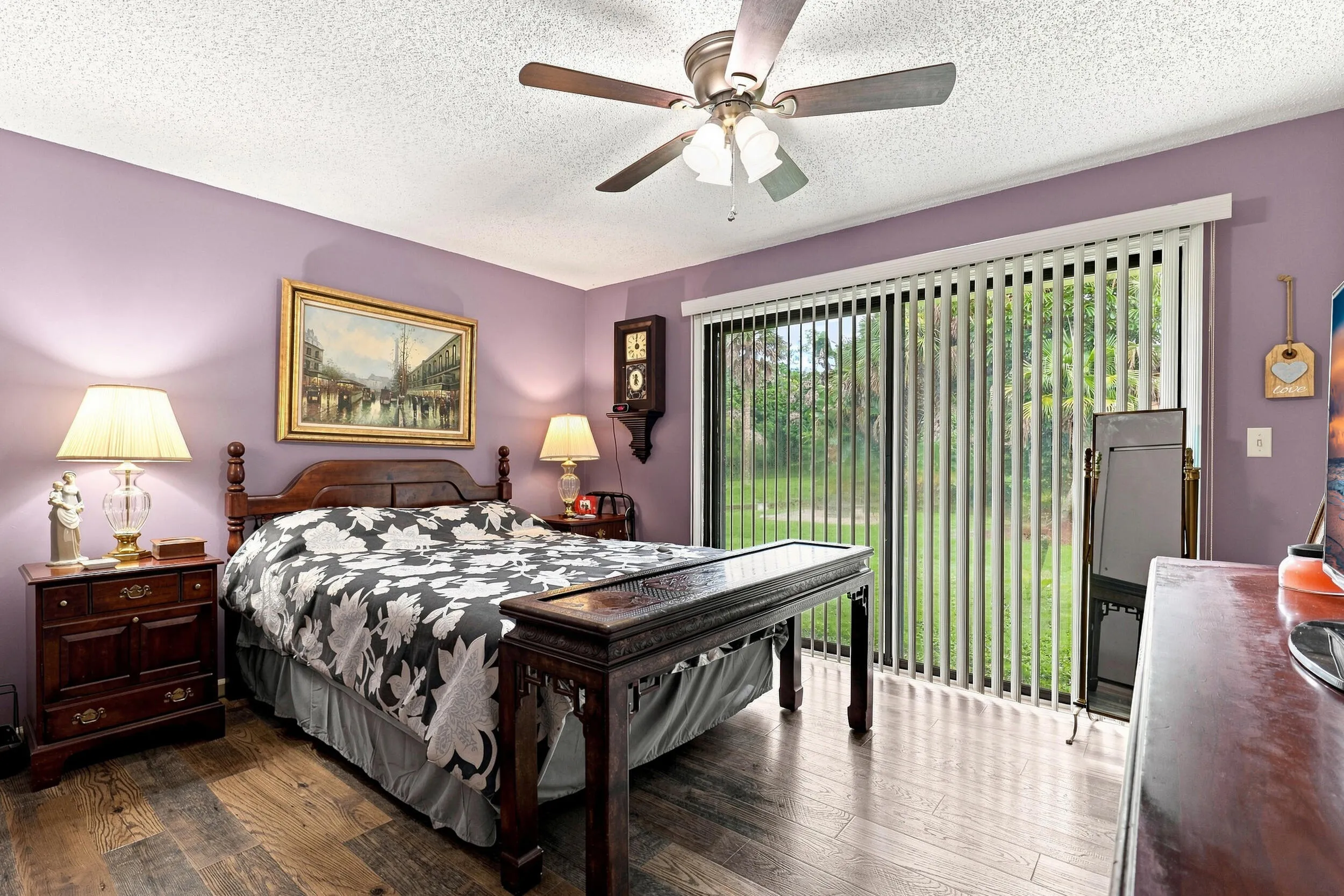 Comfortable primary bedroom with ceiling fan, updated flooring, and sliding doors overlooking the backyard.