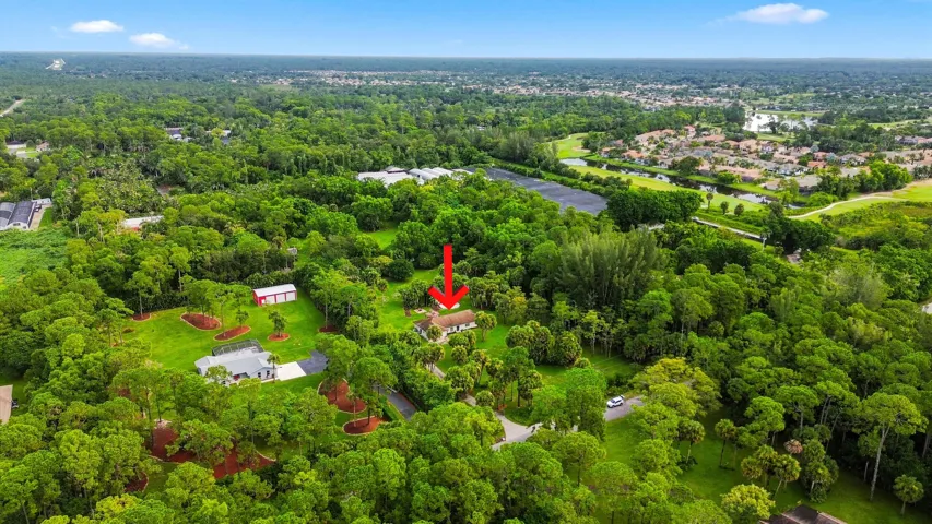 Elevated view showcasing the home’s location amid mature vegetation and neighboring acreage.