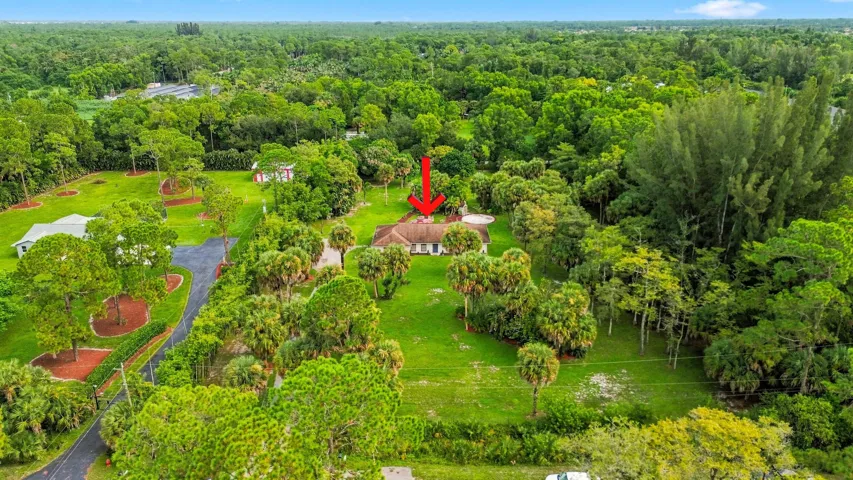 Elevated aerial view highlighting the home and its spacious acreage setting surrounded by mature trees.