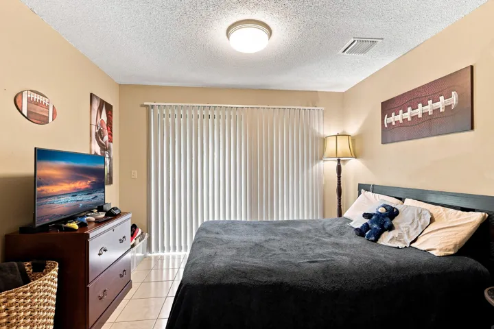Comfortable secondary bedroom with ceiling fan, natural light, and sliding doors providing outdoor views.