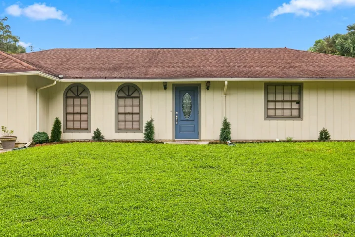 Closer exterior view showcasing the home, expansive front lawn, and covered entry.
