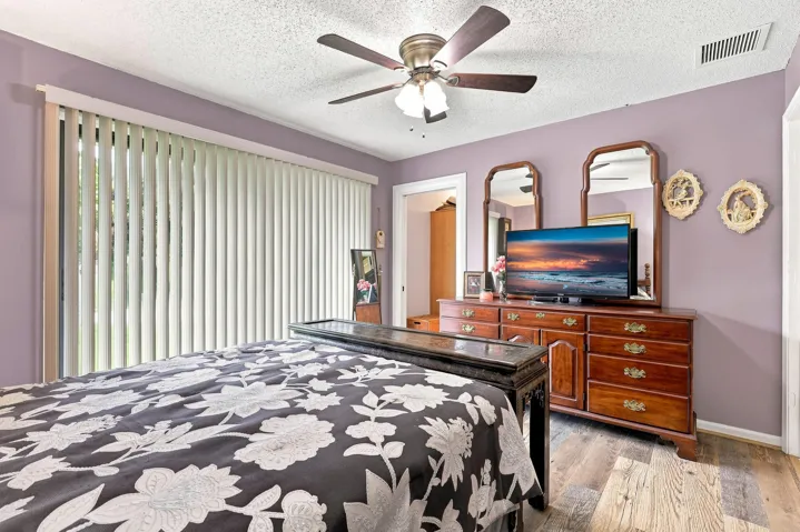 Bright bedroom featuring ceiling fan, natural light, and sliding doors overlooking the outdoor area.