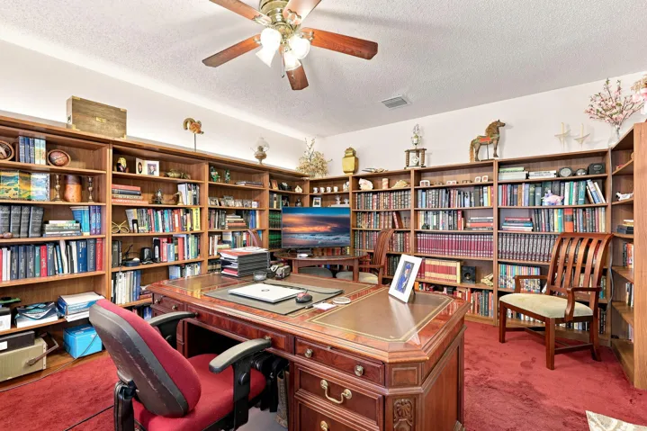 Spacious office or library with extensive built-in shelving and plenty of room for a large desk.