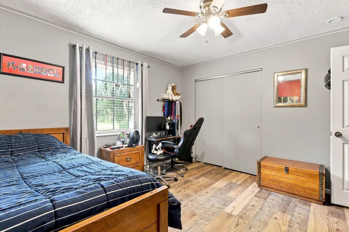 Bright secondary bedroom featuring updated flooring, ceiling fan, and closet storage.
