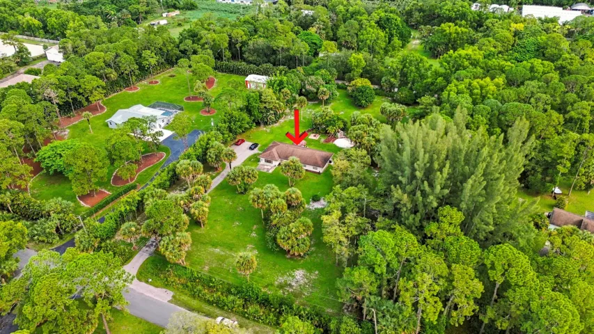 Elevated aerial view highlighting the home and its expansive acreage surrounded by mature landscaping.