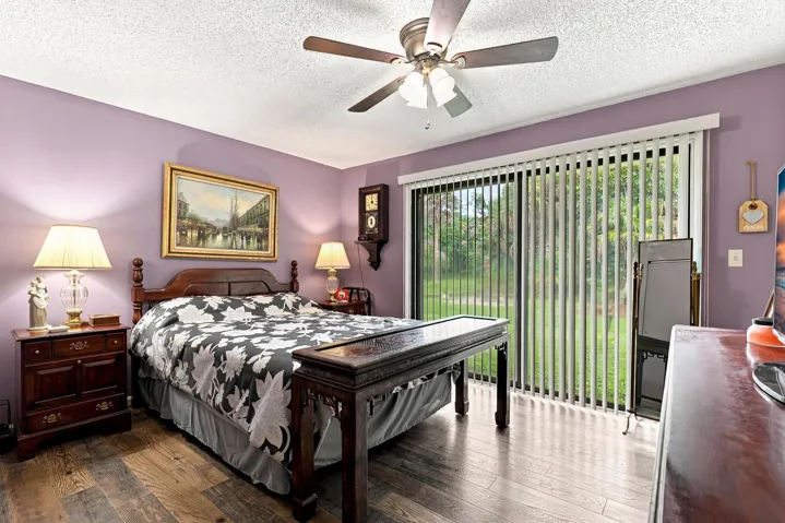 Comfortable primary bedroom with ceiling fan, updated flooring, and sliding doors overlooking the backyard.