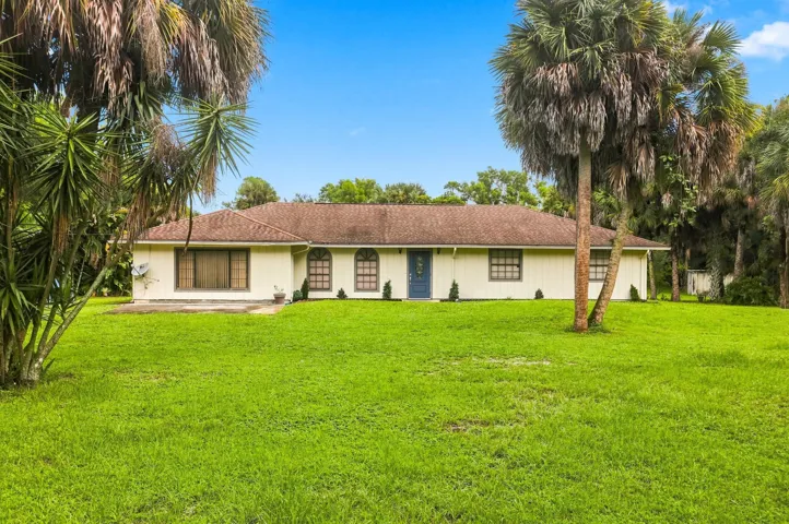 Single-story home set on a spacious lot with mature trees and a large front lawn.
