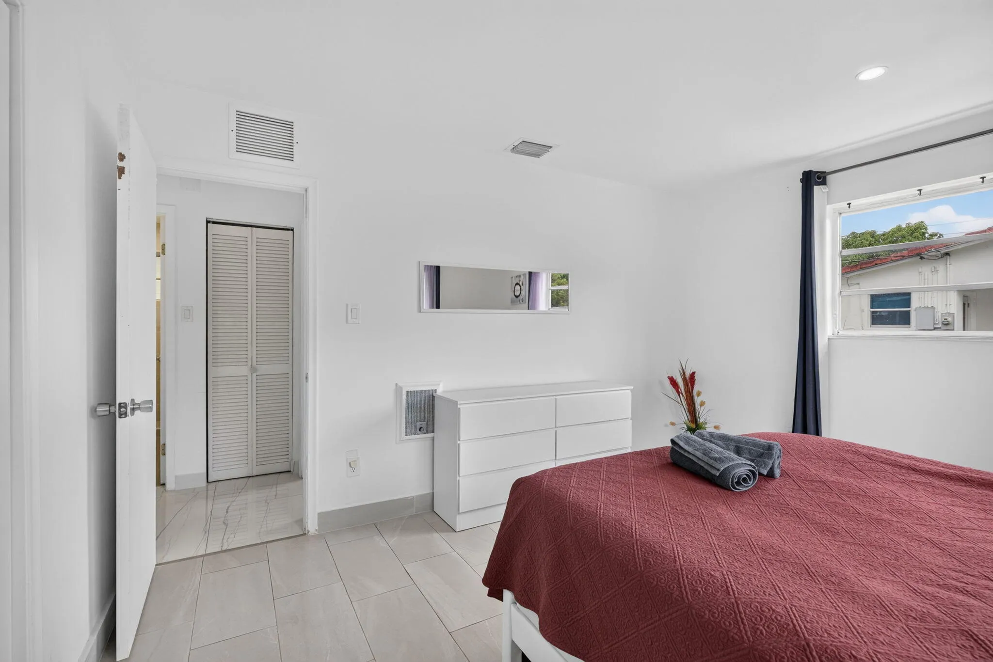 Guest Bedroom with Louvered Closet Doors and Tile Flooring